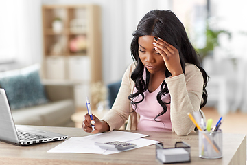 Image showing woman with calculator and papers working at home