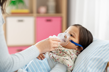 Image showing mother and sick daughter with oxygen mask in bed