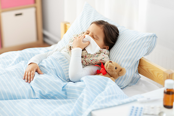 Image showing sick girl lying in bed and blowing nose at home