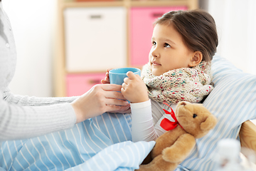 Image showing mother giving hot tea to sick little daughter