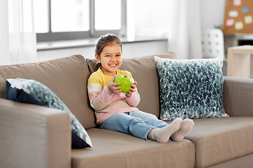 Image showing happy little girl with apple sitting on sofa