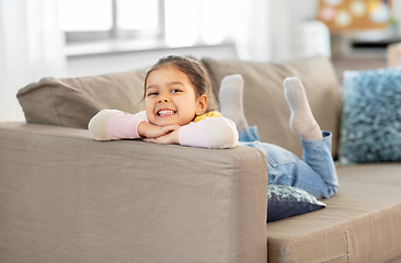 Image showing happy smiling little girl lying on sofa at home