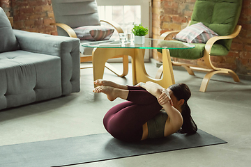 Image showing Sporty young woman practicing yoga at home