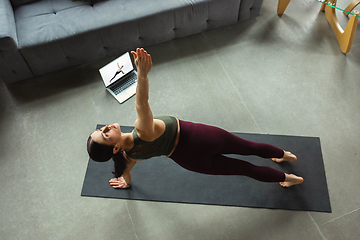 Image showing Sporty young woman taking yoga lessons online and practice at home