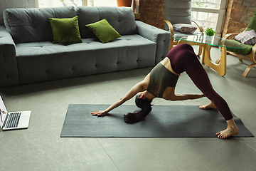 Image showing Sporty young woman taking yoga lessons online and practice at home