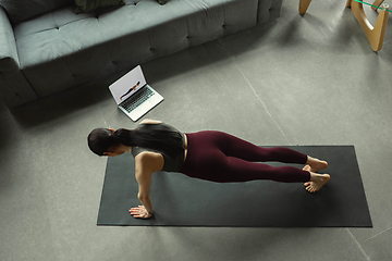 Image showing Sporty young woman taking yoga lessons online and practice at home