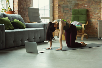 Image showing Sporty young woman taking yoga lessons online and practice at home