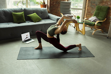 Image showing Sporty young woman taking yoga lessons online and practice at home