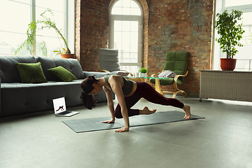 Image showing Sporty young woman taking yoga lessons online and practice at home