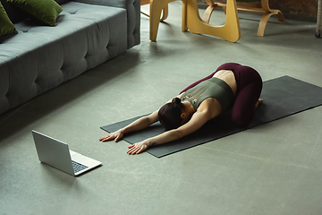 Image showing Sporty young woman taking yoga lessons online and practice at home