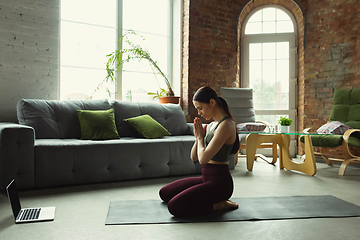 Image showing Sporty young woman taking yoga lessons online and practice at home