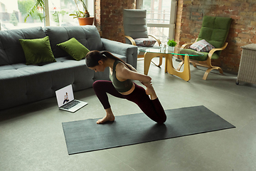 Image showing Sporty young woman taking yoga lessons online and practice at home