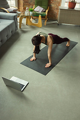 Image showing Sporty young woman taking yoga lessons online and practice at home