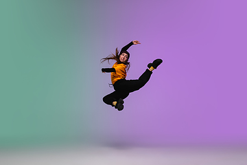 Image showing Girl dancing hip-hop in stylish clothes on gradient background at dance hall in neon light.