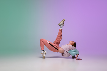 Image showing Girl dancing hip-hop in stylish clothes on gradient background at dance hall in neon light.