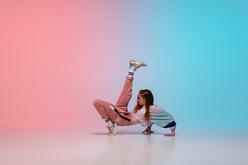 Image showing Girl dancing hip-hop in stylish clothes on gradient background at dance hall in neon light.