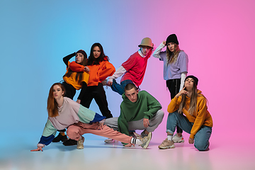 Image showing Group of dancers, boys and girls dancing hip-hop in stylish clothes on gradient studio background in neon light.