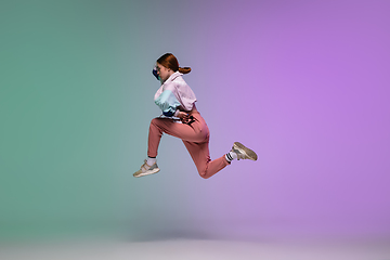 Image showing Girl dancing hip-hop in stylish clothes on gradient background at dance hall in neon light.