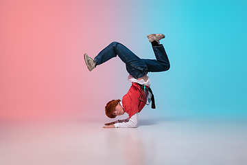 Image showing Boy dancing hip-hop in stylish clothes on gradient background at dance hall in neon light.