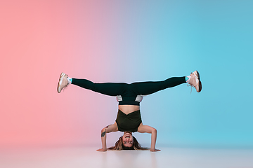 Image showing Girl dancing hip-hop in stylish clothes on gradient background at dance hall in neon light.