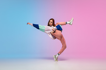 Image showing Girl dancing hip-hop in stylish clothes on gradient background at dance hall in neon light.