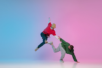 Image showing Boys dancing hip-hop in stylish clothes on gradient background at dance hall in neon light.