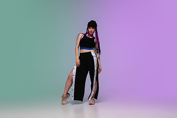 Image showing Girl dancing hip-hop in stylish clothes on gradient background at dance hall in neon light.