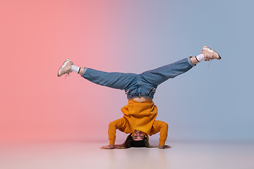 Image showing Girl dancing hip-hop in stylish clothes on gradient background at dance hall in neon light.