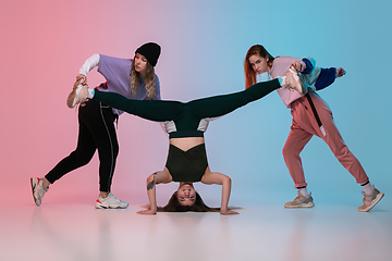 Image showing Girls dancing hip-hop in stylish clothes on gradient background at dance hall in neon light.