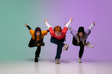 Image showing Group of teens, boys and girls dancing hip-hop in stylish clothes on gradient studio background in neon light.