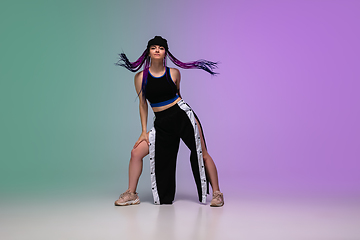 Image showing Girl dancing hip-hop in stylish clothes on gradient background at dance hall in neon light.