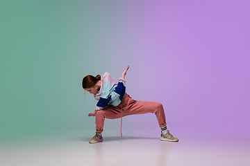 Image showing Girl dancing hip-hop in stylish clothes on gradient background at dance hall in neon light.