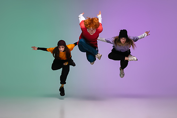 Image showing Group of teens, boys and girls dancing hip-hop in stylish clothes on gradient studio background in neon light.