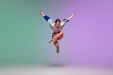 Image showing Girl dancing hip-hop in stylish clothes on gradient background at dance hall in neon light.