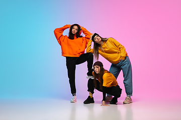 Image showing Girls dancing hip-hop in stylish clothes on gradient background at dance hall in neon light.