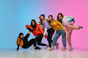 Image showing Group of dancers, boys and girls dancing hip-hop in stylish clothes on gradient studio background in neon light.