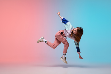 Image showing Girl dancing hip-hop in stylish clothes on gradient background at dance hall in neon light.