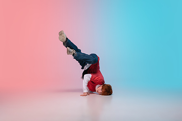 Image showing Boy dancing hip-hop in stylish clothes on gradient background at dance hall in neon light.