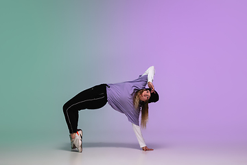 Image showing Girl dancing hip-hop in stylish clothes on gradient background at dance hall in neon light.