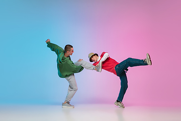 Image showing Boys dancing hip-hop in stylish clothes on gradient background at dance hall in neon light.