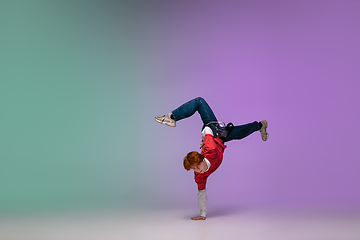 Image showing Boy dancing hip-hop in stylish clothes on gradient background at dance hall in neon light.