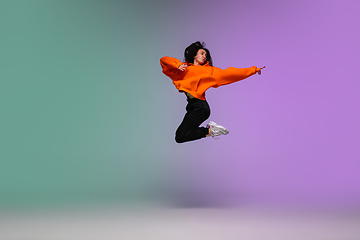 Image showing Girl dancing hip-hop in stylish clothes on gradient background at dance hall in neon light.