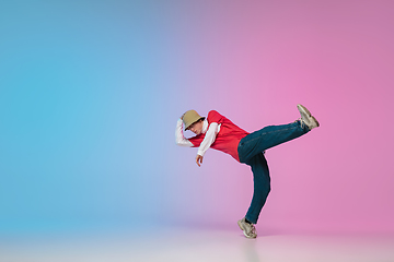 Image showing Boy dancing hip-hop in stylish clothes on gradient background at dance hall in neon light.