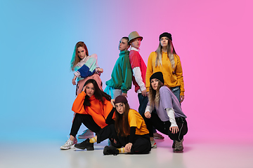 Image showing Group of dancers, boys and girls dancing hip-hop in stylish clothes on gradient studio background in neon light.