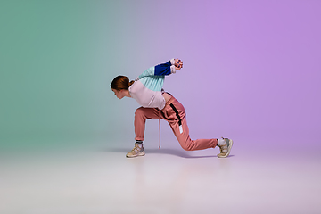 Image showing Girl dancing hip-hop in stylish clothes on gradient background at dance hall in neon light.