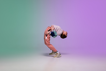 Image showing Girl dancing hip-hop in stylish clothes on gradient background at dance hall in neon light.