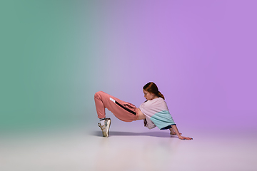 Image showing Girl dancing hip-hop in stylish clothes on gradient background at dance hall in neon light.