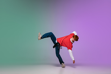 Image showing Boy dancing hip-hop in stylish clothes on gradient background at dance hall in neon light.