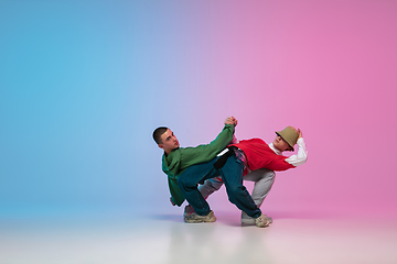 Image showing Boys dancing hip-hop in stylish clothes on gradient background at dance hall in neon light.