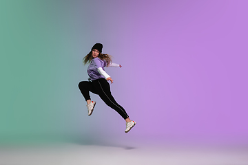 Image showing Girl dancing hip-hop in stylish clothes on gradient background at dance hall in neon light.